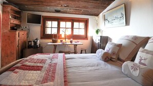 A cozy room with a bed, a wooden cabinet, a table with a lamp, and a window with curtains. - Chambre Cabuche with POrivate Jacuzzi (Chamonix Mont-Blanc)