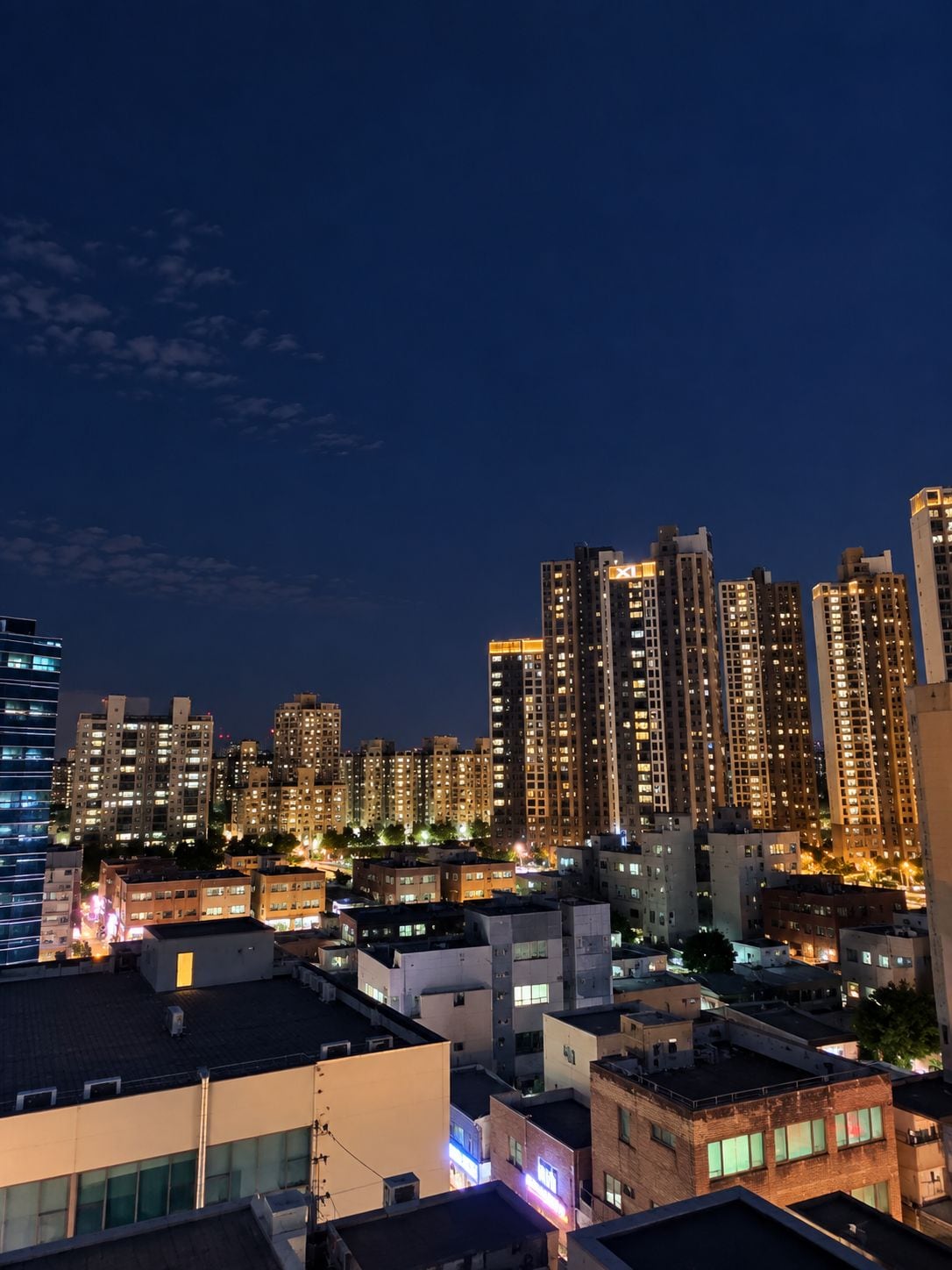 A nighttime cityscape with high-rise buildings, some with illuminated windows.