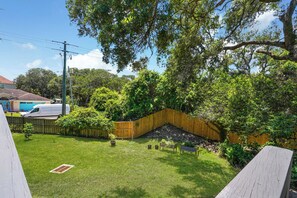 A backyard with a wooden fence, a grassy lawn, and a tree. - Anastasia Oaks 206B High Tide (St. Augustine)