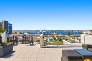 Eine Dachterrasse mit Sitzgelegenheiten im Freien, Blick auf den Yachthafen und einem strahlend blauen Himmel.