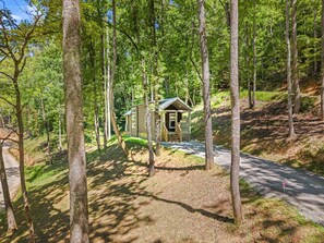 A cabin surrounded by tall trees with a gravel path leading to it. - A Tiny Slice of Paradise (Bryson City)