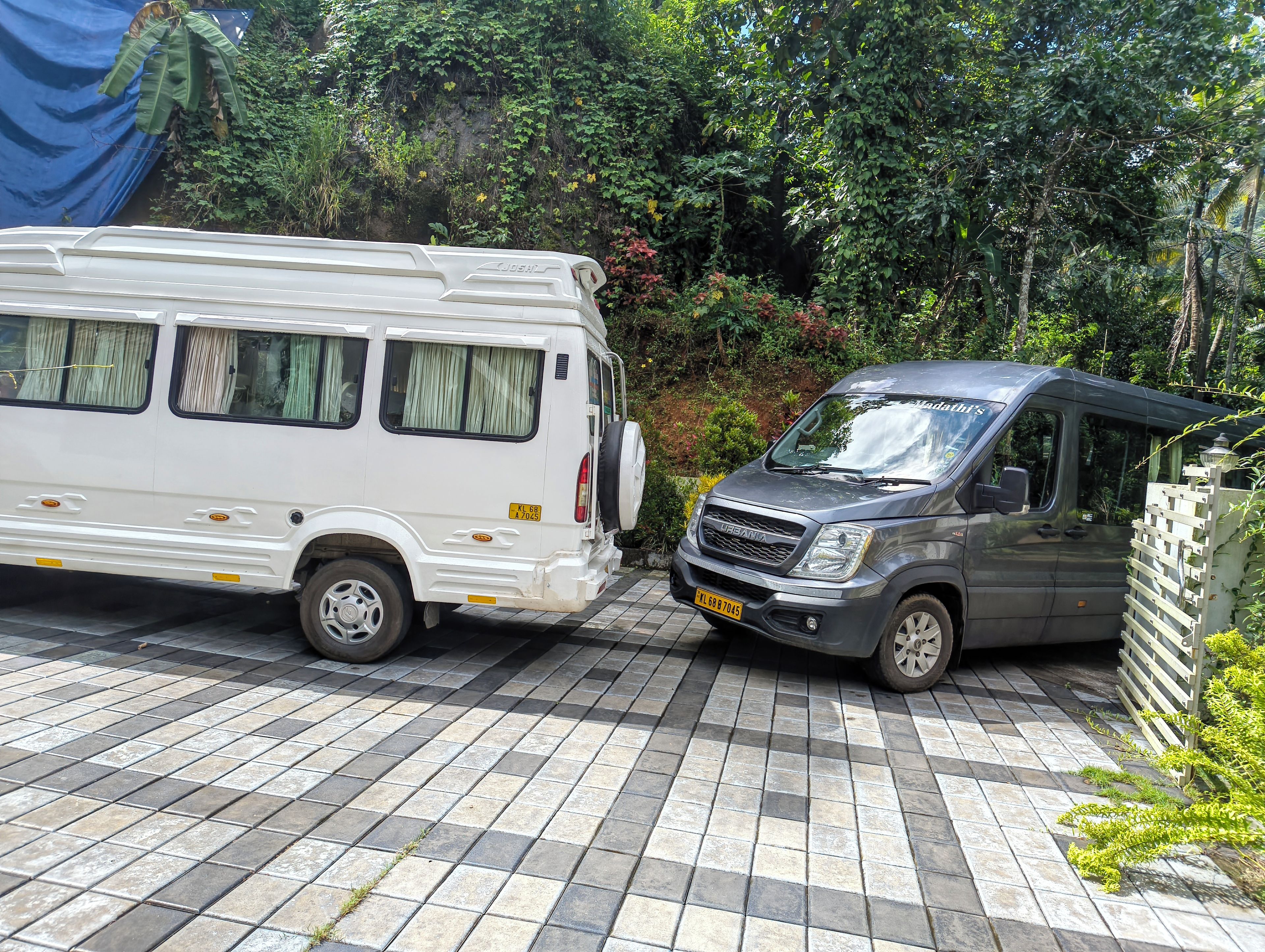 Two vehicles parked on a tiled surface with greenery in the background.