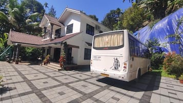 Een bus geparkeerd voor een gebouw met twee verdiepingen en een entree met betegelde vloer.