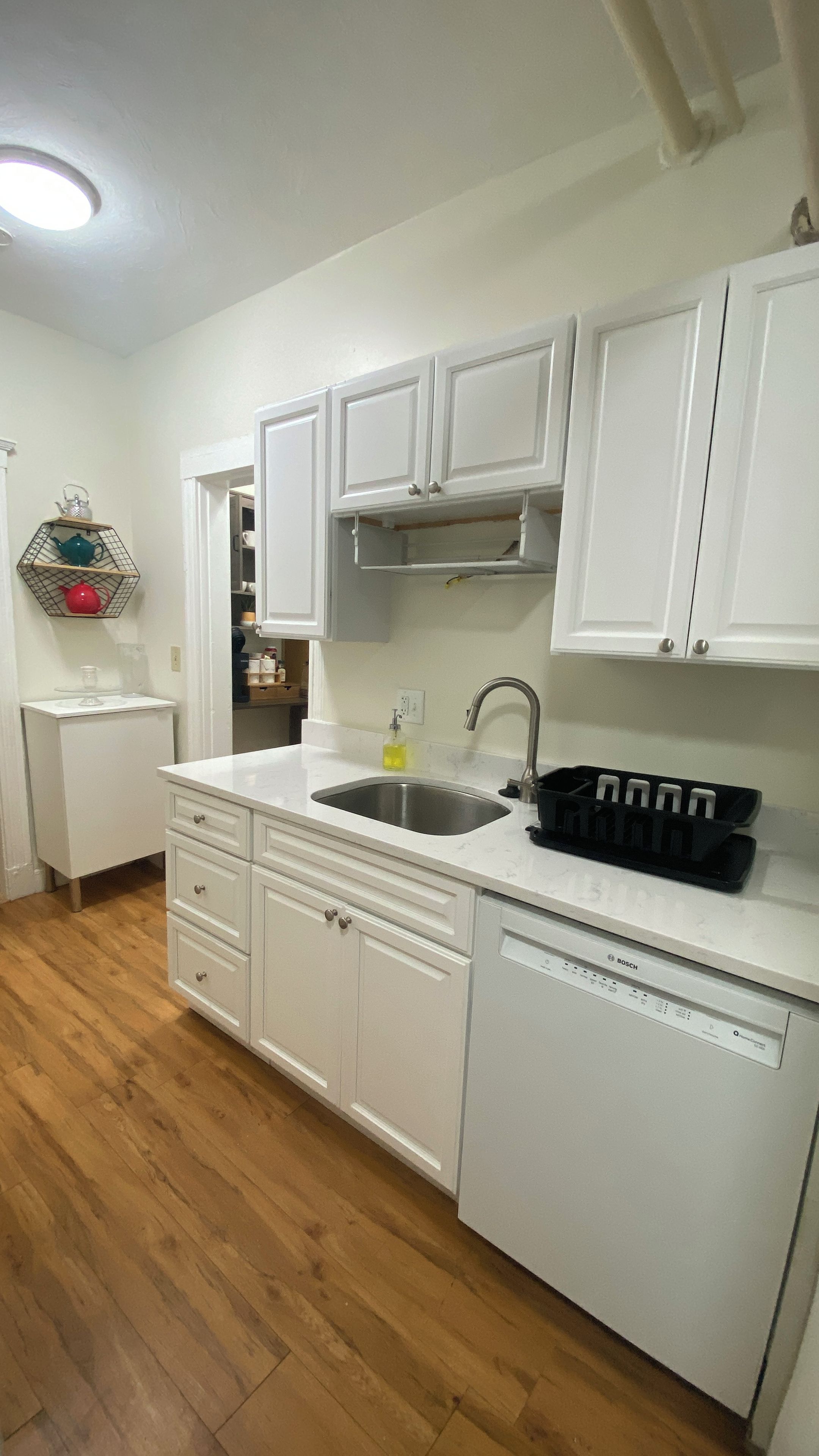 A kitchen with white cabinets, a stainless steel sink, and a Bosch dishwasher.