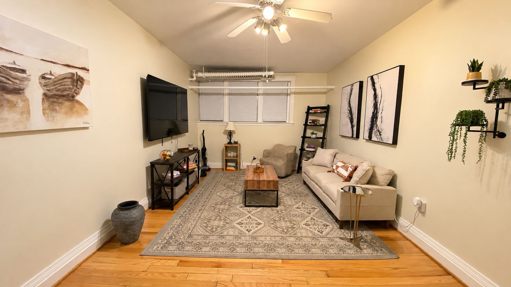 A living room with a sofa, coffee table, TV, and artwork.