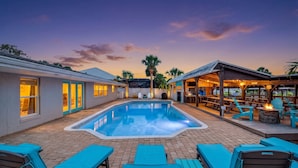 A swimming pool with lounge chairs and a covered patio area. - Canal-Front Beach Home | 5BR/4BA | Private Pool + Boat Dock (Flagler Beach)