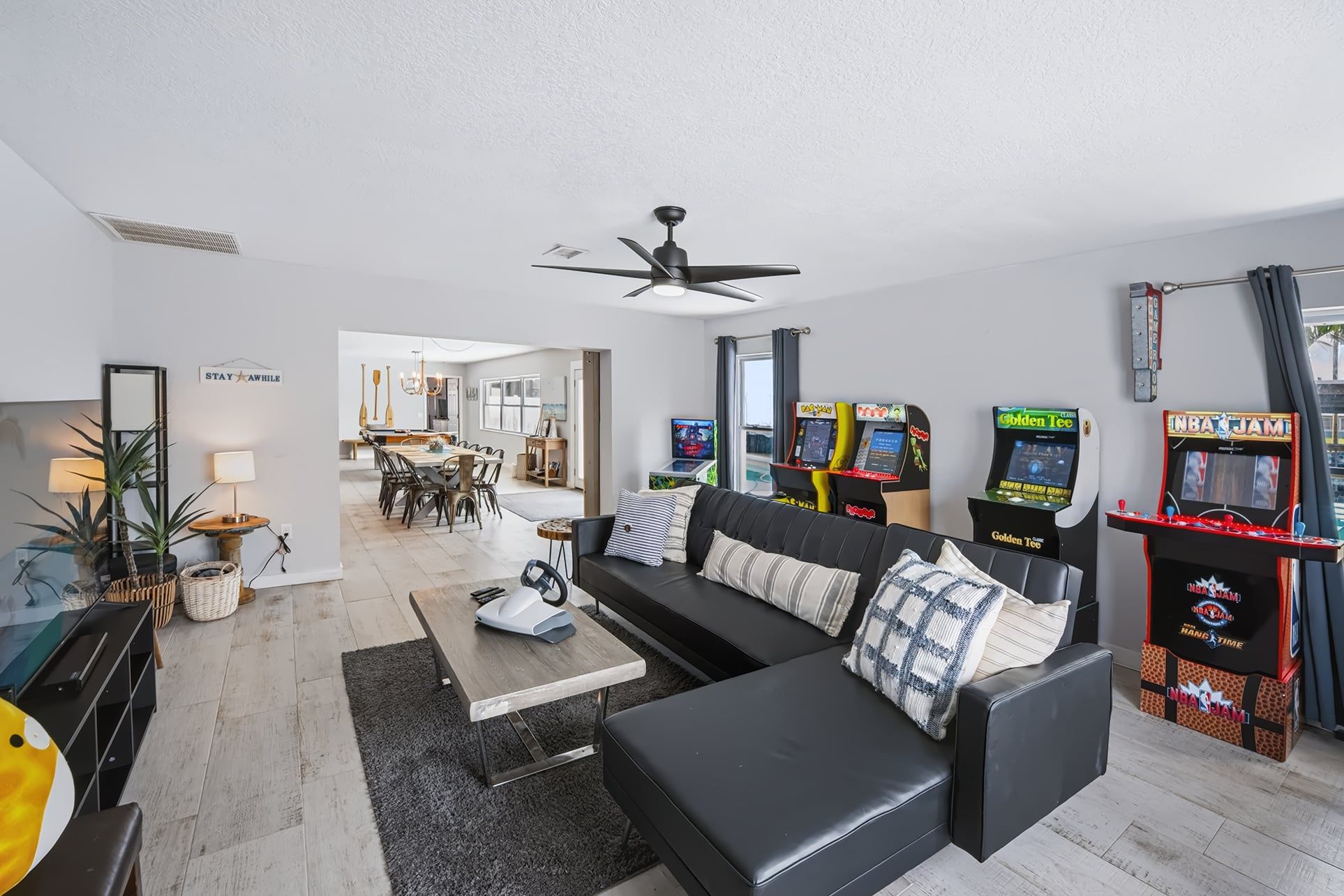 Ein modernes Wohnzimmer mit einem schwarzen Ledersofa, einem Couchtisch und Spielautomaten.