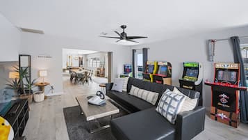 Ein modernes Wohnzimmer mit einem schwarzen Ledersofa, einem Couchtisch und Spielautomaten.