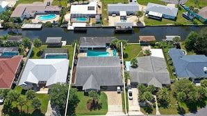 An aerial view of a residential area with houses, a swimming pool, and a canal. - Canal-Front Beach Home | 5BR/4BA | Private Pool + Boat Dock (Flagler Beach)