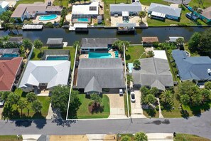 An aerial view of a residential area with houses, a swimming pool, and a canal. - Canal-Front Beach Home | 5BR/4BA | Private Pool + Boat Dock (Flagler Beach)