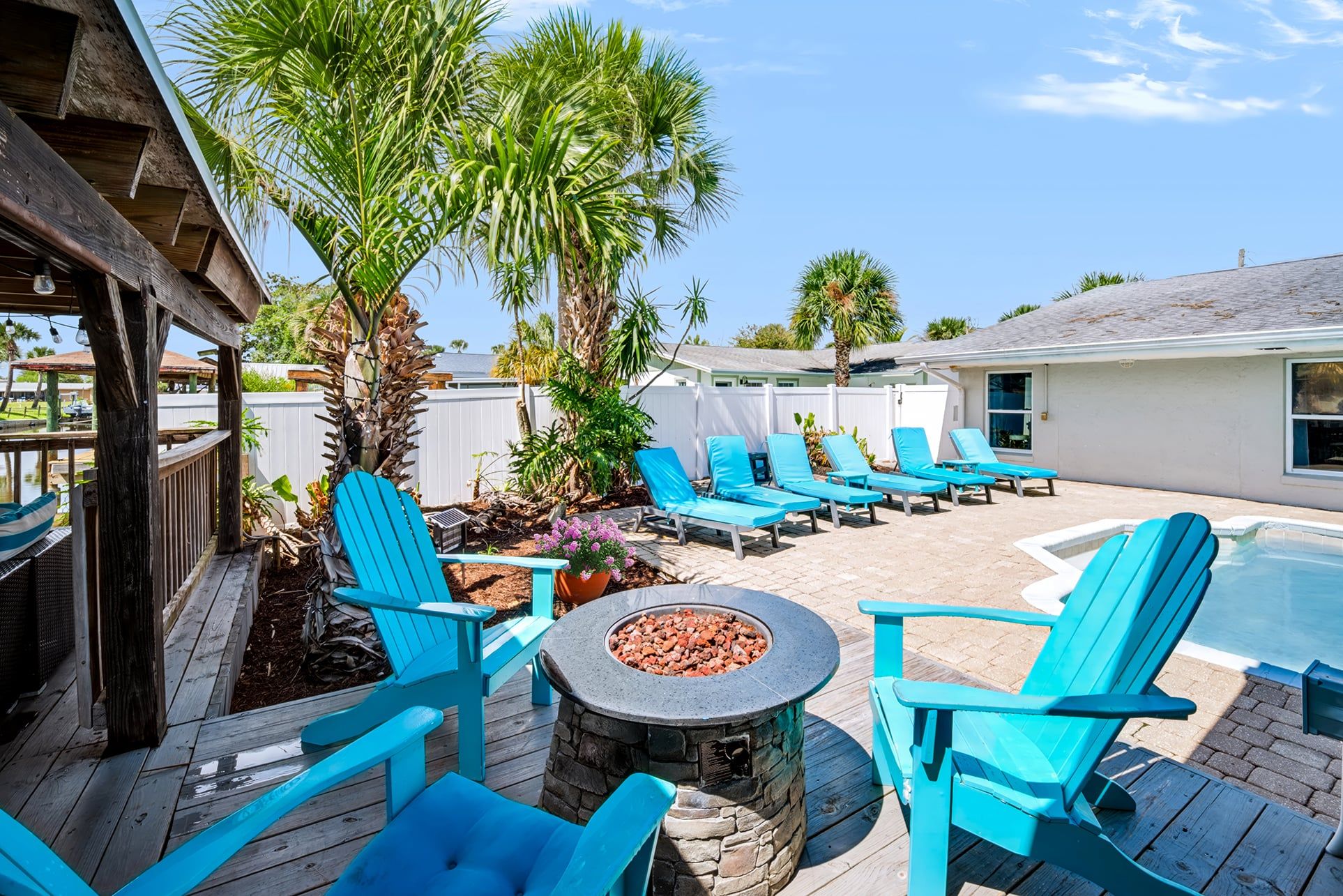 An outdoor patio area with a fire pit, lounge chairs, and a pool.