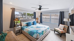 A bedroom with a bed, a chair, a ceiling fan, and a window. - Canal-Front Beach Home | 5BR/4BA | Private Pool + Boat Dock (Flagler Beach)