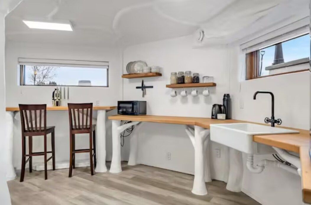 Une cuisine compacte dotée d’un plan de travail en bois, de meubles blancs et d’une fenêtre laissant entrer la lumière naturelle.
