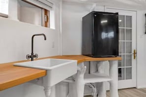 A modern kitchen with a white countertop, a black refrigerator, and a wooden cabinet.