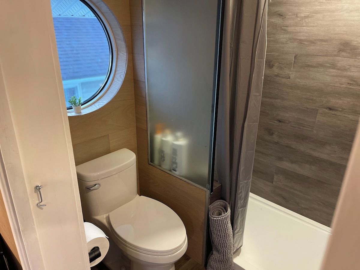 Une petite salle de bain comprenant des toilettes, une petite fenêtre et un espace douche.