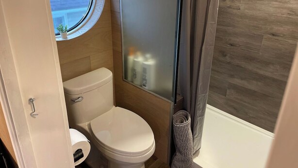 Une petite salle de bain comprenant des toilettes, une petite fenêtre et un espace douche.