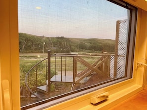 A window with a view of a wooden deck and a metal railing.