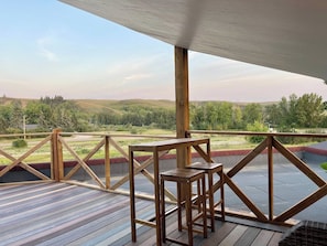 An outdoor deck with a wooden railing, a table, and chairs.
