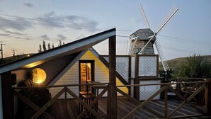 Une terrasse en bois avec un moulin à vent en arrière-plan.