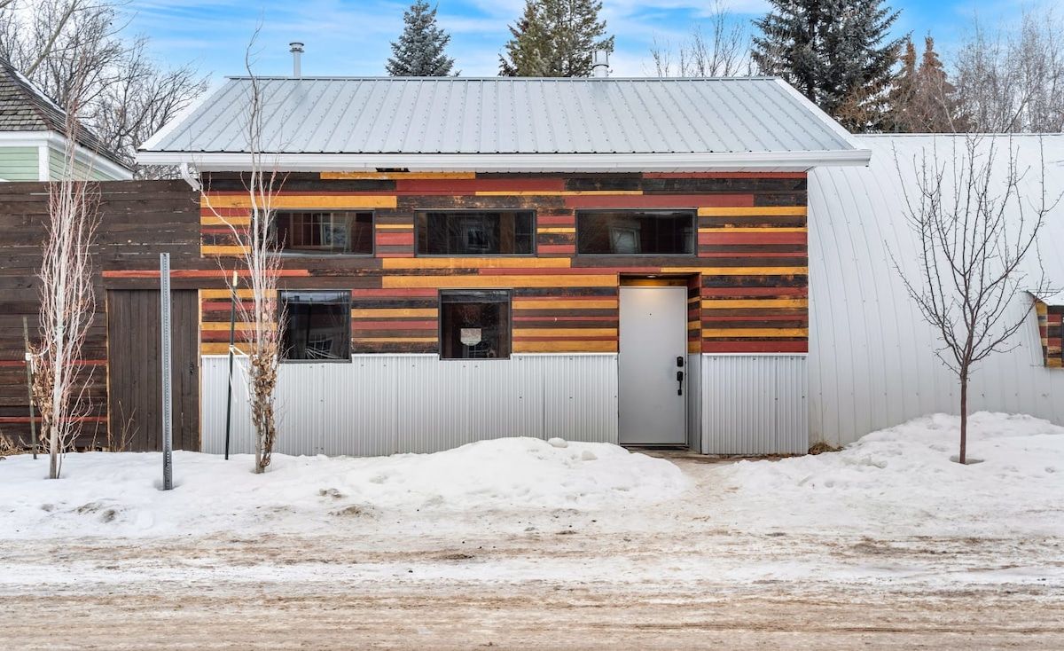 Un bâtiment à deux étages, doté d’un toit en pente, d’une clôture en bois et d’un sol recouvert de neige.