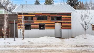 Un bâtiment à deux étages, doté d’un toit en pente, d’une clôture en bois et d’un sol recouvert de neige.