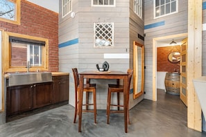 A kitchen with a sink, a table with chairs, and a window. - Historic Firehall Guesthouse with Private Covered Patio & Wood Stove (Rosebud)