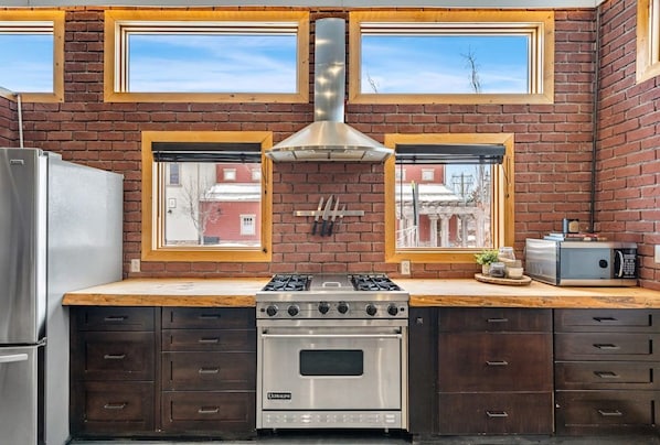 A kitchen with a stainless steel stove, oven, and a window with a view of buildings.