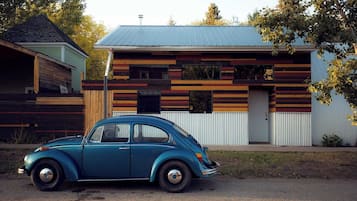 Ein Oldtimer vor einem modernen Haus mit geneigtem Dach und horizontalen Holzpaneelen.