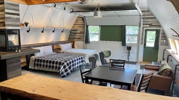 Un espacio habitable pequeño con cama, mesa de comedor y zona de kitchenette.