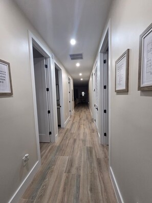 A hallway with wooden flooring, white walls, and doors leading to rooms. - Marvelous 4-bedroom House Near Beaches (Hollywood)