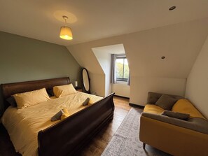 Een slaapkamer met een bed, een stoel, een spiegel en een raam.