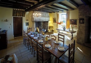 A dining room with a long wooden table set for a meal, a stone fireplace, and a chandelier. - Group Retreat for 40 guests - Pools, Gardens & Bbq (Pechs-de-l'Esperance)