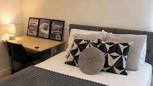 Ett välordnat hotellrum med en säng, ett skrivbord och en stol. Det finns tre inramade tavlor på väggen.