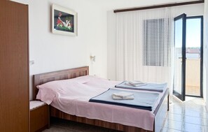 A bedroom with a bed, a bedside table, a window with curtains, and a door leading to an outdoor area. - Lovely apartment in Medulin with WiFi (Medulin)