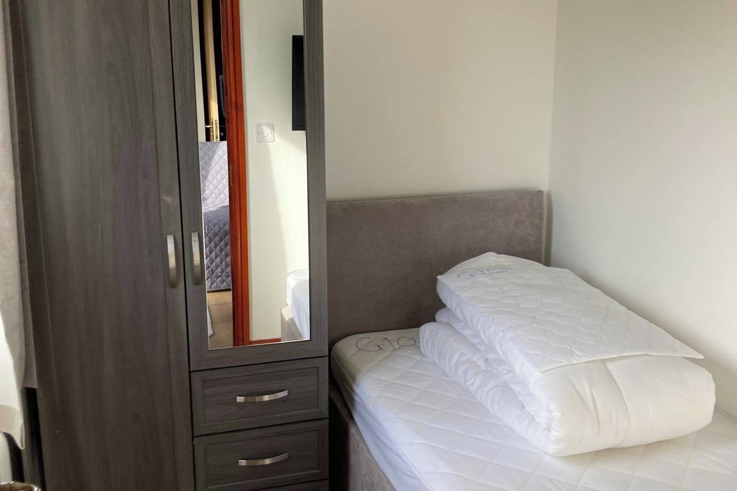 Een kamer met een bed, een kast en een spiegel.