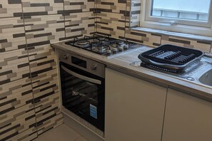 A kitchen with a gas stove, oven, and a black grill on the countertop. - Central Stratford Gem (London)