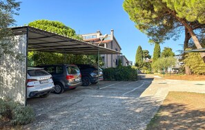 A covered parking area with two cars parked, a building with a sloped roof, and a clear sky. - Stunning apartment in Medulin with WiFi (Medulin)