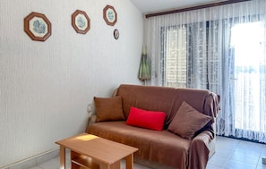 A living room with a brown sofa, a red pillow, and a wooden coffee table. There are three framed pictures on the wall. - Stunning apartment in Medulin with WiFi (Medulin)
