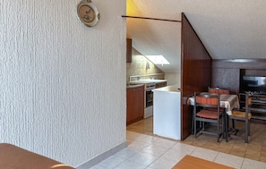 A compact kitchen with a dining area, a small refrigerator, and a television. - Stunning apartment in Medulin with WiFi (Medulin)