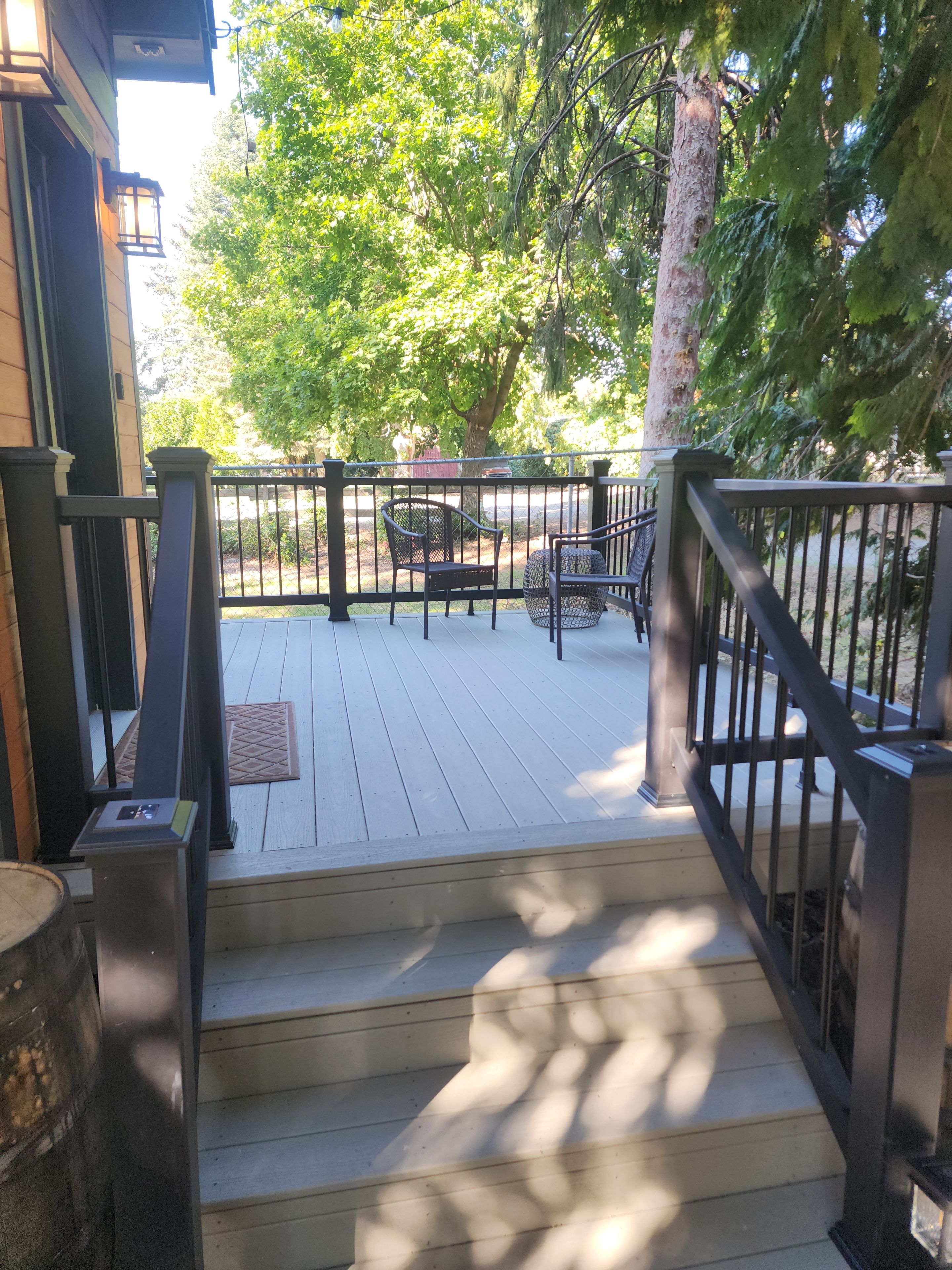 A wooden deck with a metal railing, a bench, and a chair.