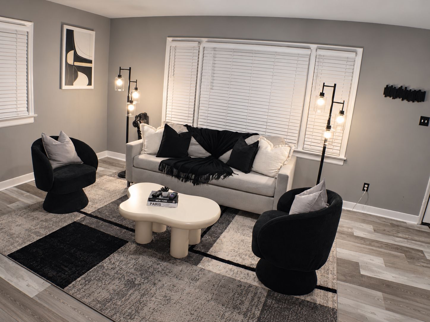 A modern living room with a sofa, two armchairs, a coffee table, and a floor lamp.