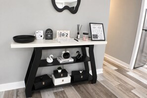 A white desk with a black frame, a calendar, a framed document, a white swan, a black swan, and a black speaker.