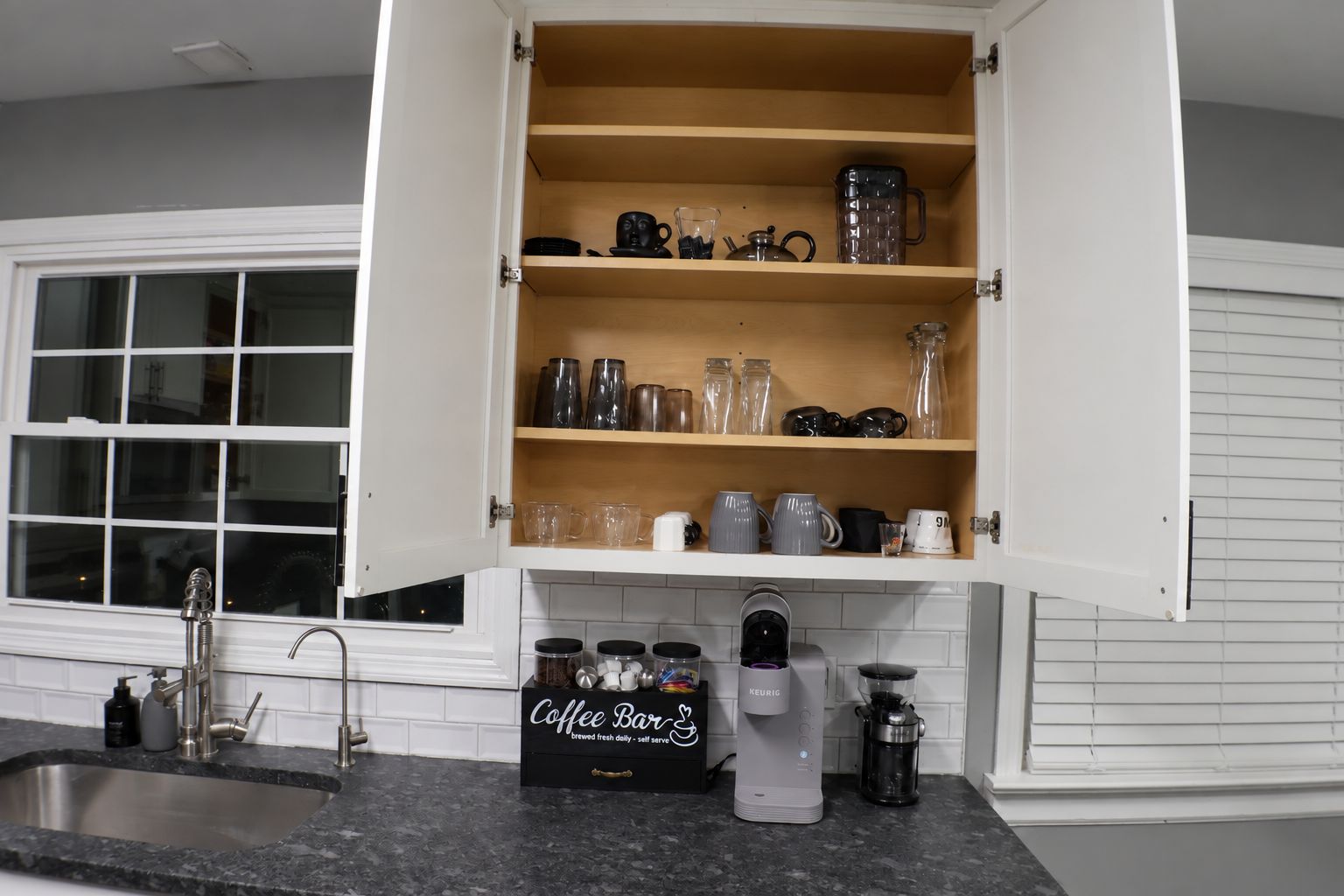 Een keuken met een koffiebar, een spoelbak en een raam.