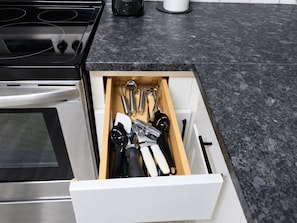 A kitchen drawer with various utensils and a coffee maker.