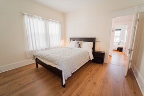 A bedroom with a large bed, a nightstand, and a door leading to another room. - 2336A- Upper 3B2B Unit w/ Laundry near UC Berkeley (Berkeley)