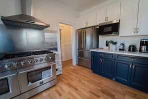 A modern kitchen with stainless steel appliances, wooden flooring, and white cabinetry. - 2336A- Upper 3B2B Unit w/ Laundry near UC Berkeley (Berkeley)