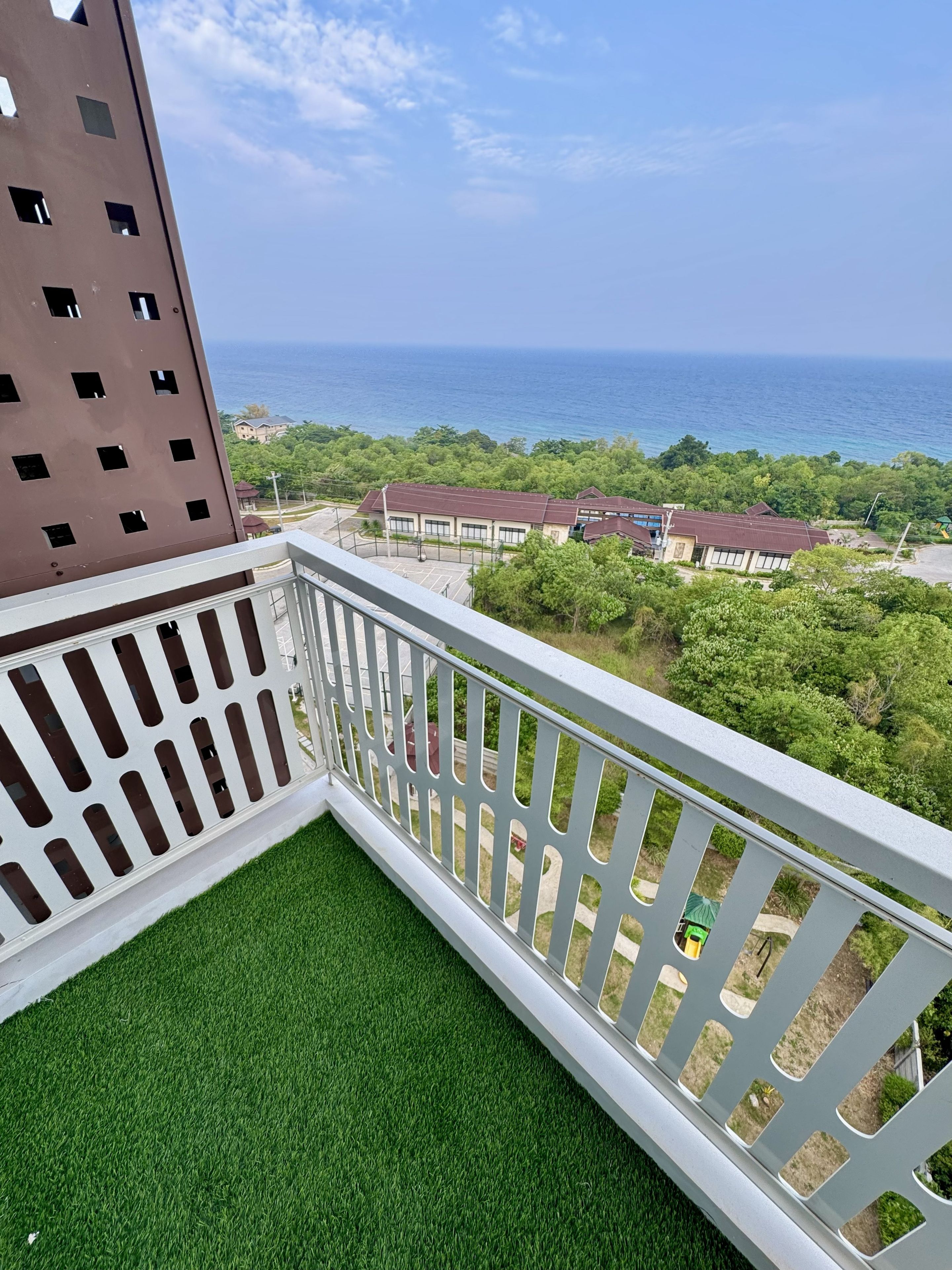 A balcony with a view of the sea and a building with multiple windows.