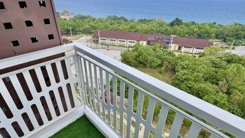 A balcony with a view of the sea and a building with multiple windows.
