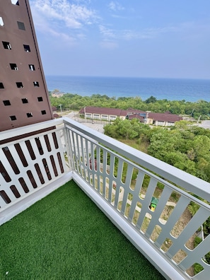 Un balcon avec vue sur la mer et un immeuble doté de nombreuses fenêtres.