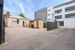 A parking lot with a gated entrance, a building with a flat roof, and a modern structure with large windows.